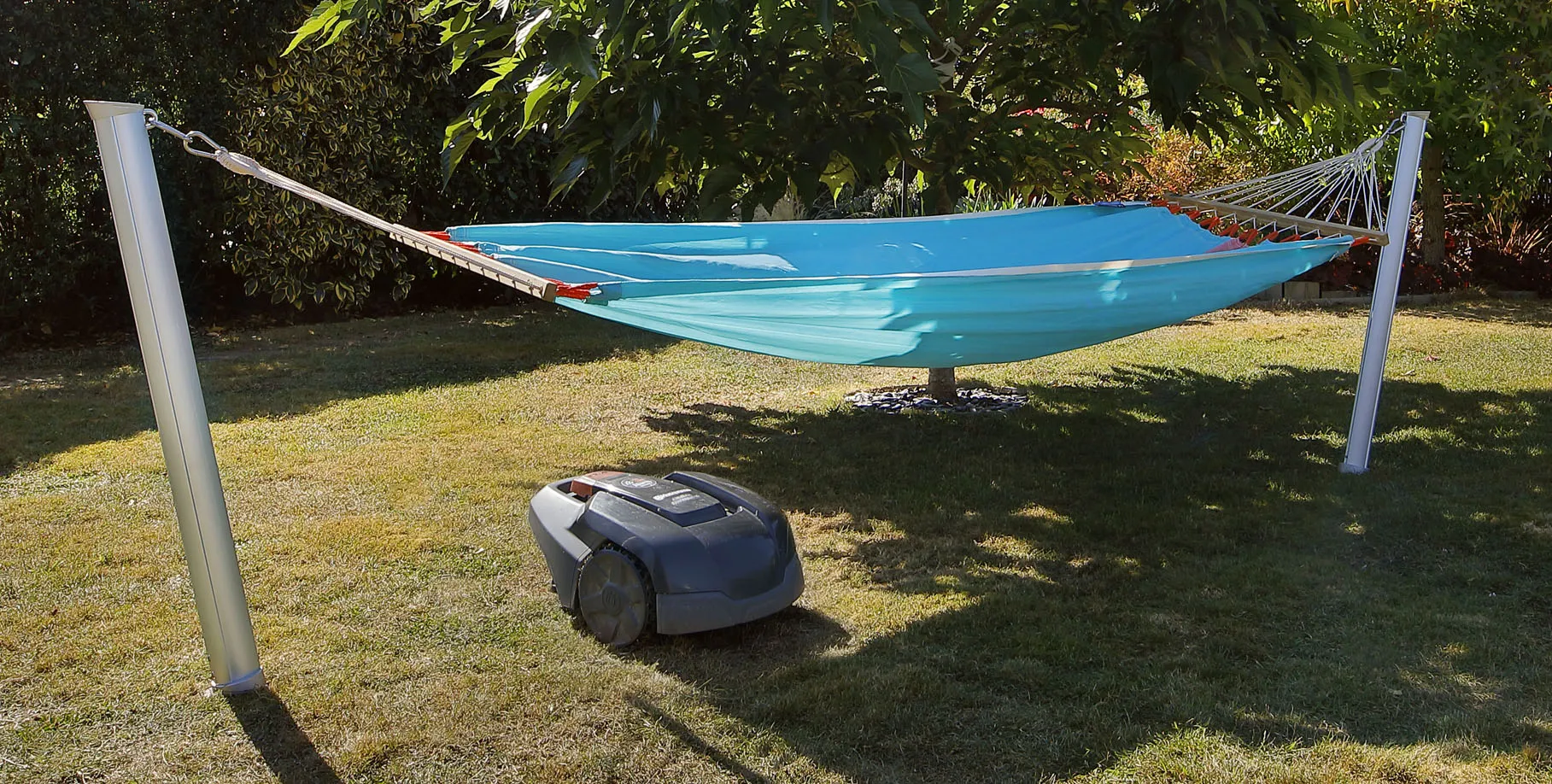 vue montrant un robot tondeuse circulant librement sous un hamac suspendu sur poteaux Gard&Rock, sol dégagé sans structure gênante